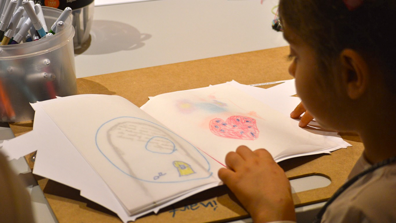 Criança folheia um caderno de desenhos