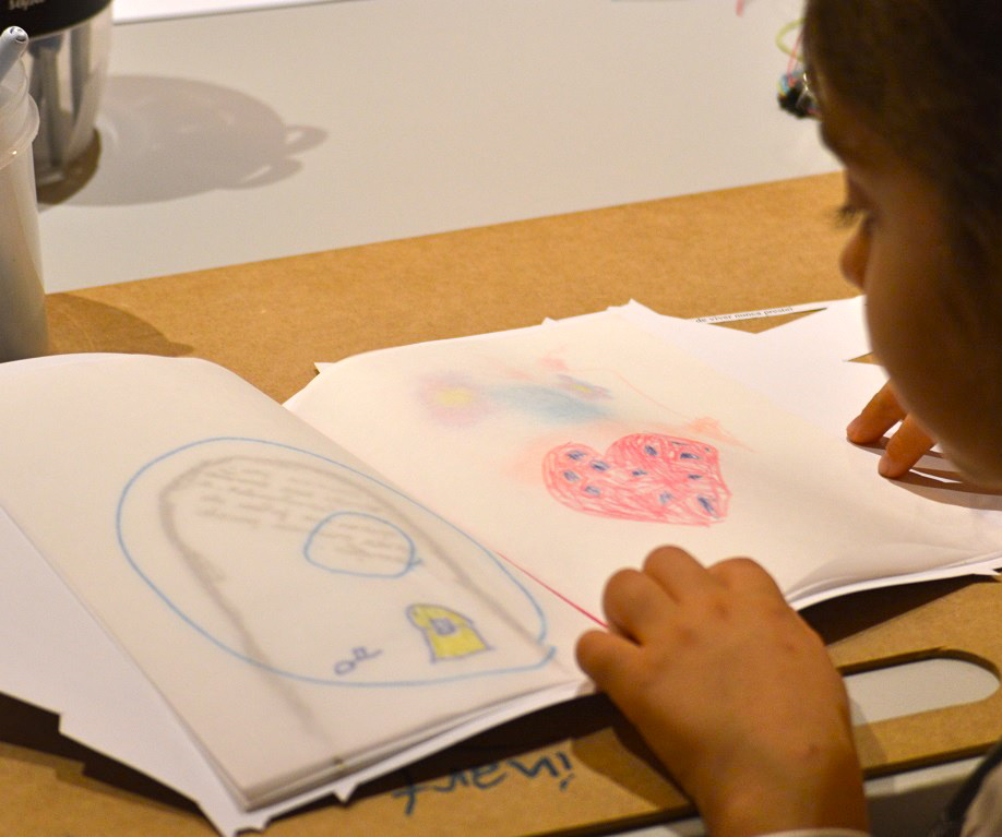 Criança folheia um caderno de desenhos