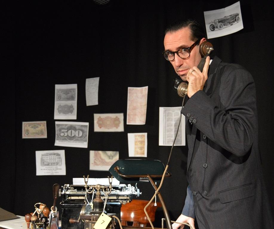 Ator encarnando "Alves Reis" atende o telefone em palco