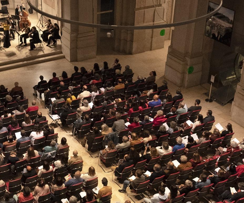 Pessoas sentadas na plateia assistem a um concerto